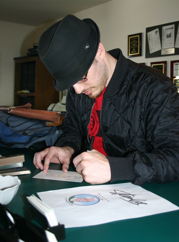 Aaron D'Errico autographs a photo during a recent visit to The Journal office. The aspiring illustrator placed third and eighth in voter and judges balloting in a logo contest for the Stan Lee Foundation.