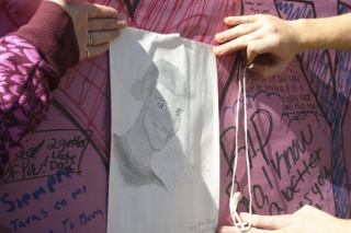 Friends of Jermaine Reaves hang a sketch of him on a memorial banner overlooking Sunken Park