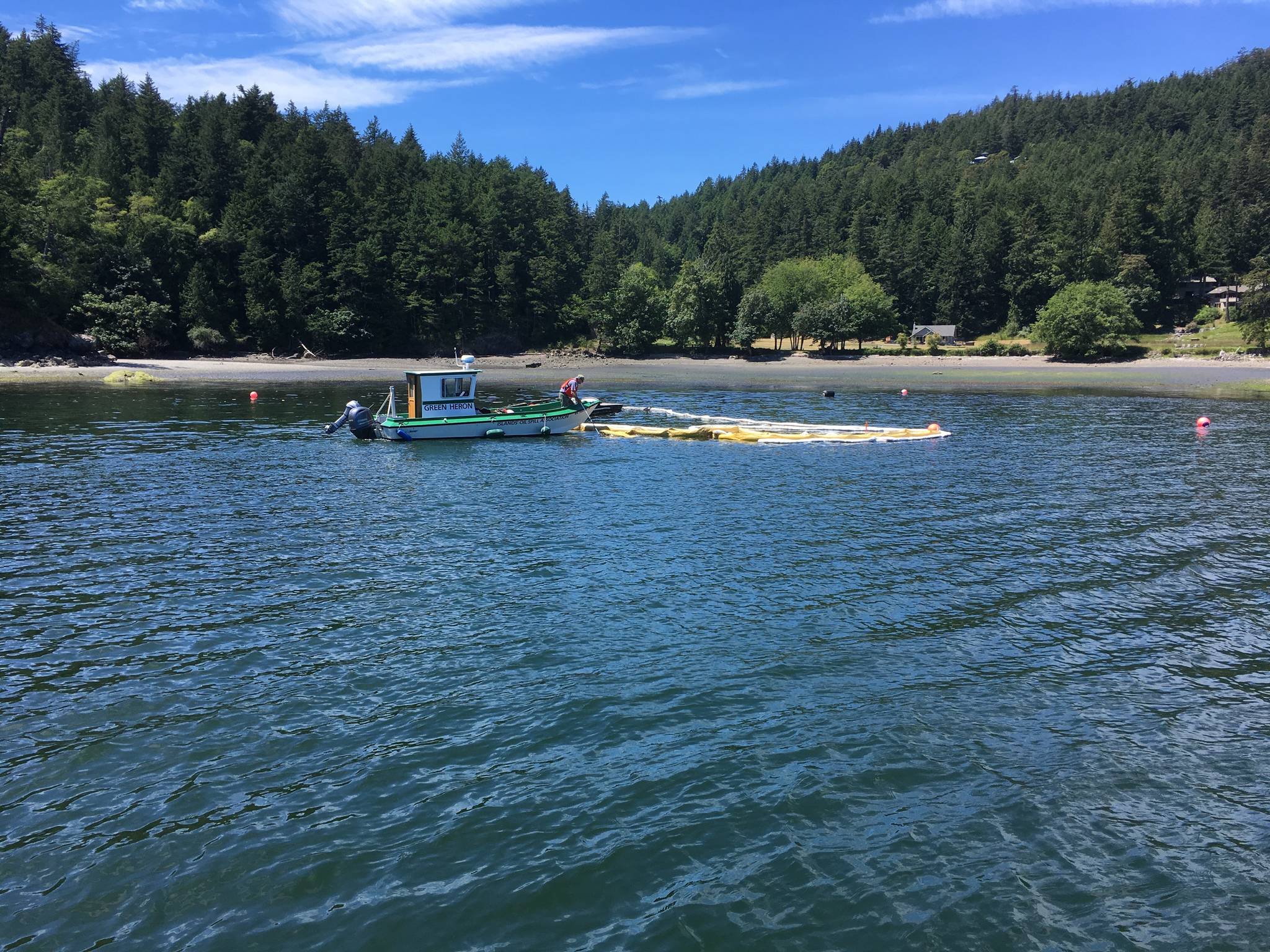 Contributed photo./ Allen Rosenberg. Jerry McElyea helps retrieve oil containment boom after the spill in Judd Cove. Ken Weatherill is driving one of IOSAs response vessels, The Green Heron.